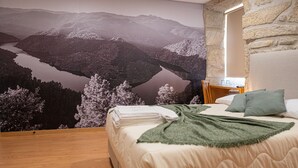A bedroom with a bed, a nightstand, a mirror, and a wall mural of a mountainous landscape. - The Village House by CDV (Carrazeda de Ansiaes)