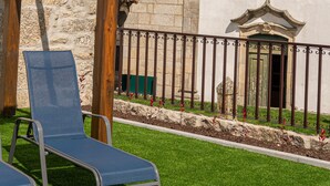 A pool area with lounge chairs, a stone building with a clock, and a fence. - The Village House by CDV (Carrazeda de Ansiaes)