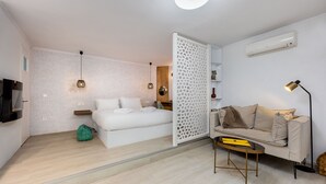 A modern bedroom with a bed, a sofa, a coffee table, and a TV. - Seaside Nestie by BluPine (Vari-Voula-Vouliagmeni)