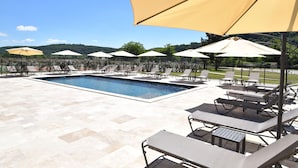 A poolside area with lounge chairs and umbrellas. - Hotel le Périgord (La Roque-Gageac)