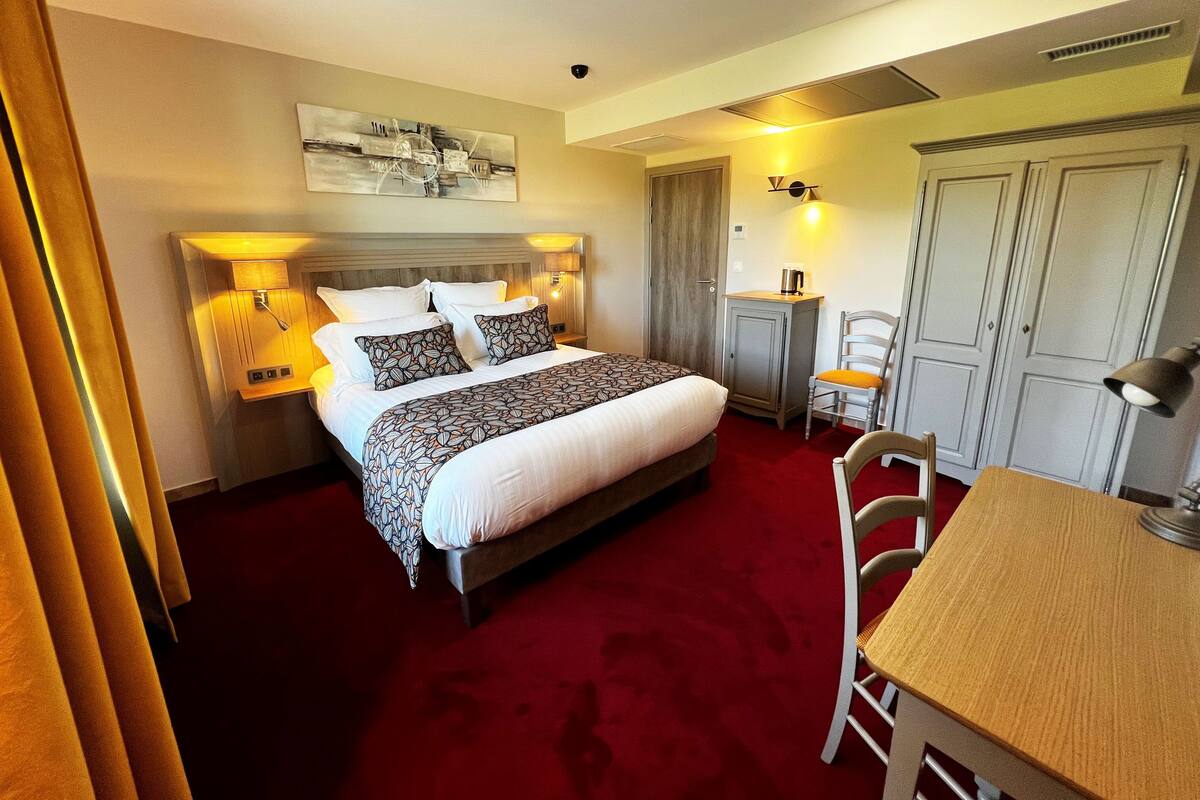 A hotel room with a large bed, bedside tables, a desk, and a chair.