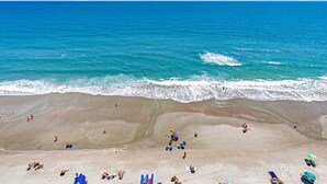 Une plage avec des gens, des parasols et des chaises de plage.