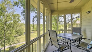 A covered patio with a table and chairs, large windows, and a view of a green landscape. - Sea Trail Resort Villas Condo w/ Community Perks! (Sunset Beach)