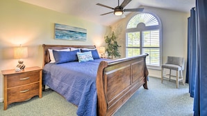 A bedroom with a wooden bed, a nightstand, a chair, a ceiling fan, and a window with blinds. - Sea Trail Resort Villas Condo w/ Community Perks! (Sunset Beach)
