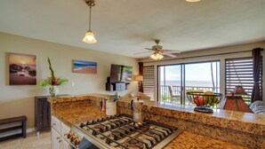 Cocina con encimeras de granito, estufa a gas, ventilador de techo y grandes ventanales con vistas panorámicas.