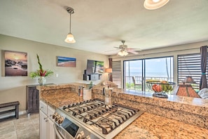 Enjoy cooking in this well-equipped kitchen with a large island, ceiling fan, and ocean views through large windows.