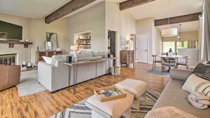 A spacious living area with a fireplace, a sofa, a dining table, and a kitchen in the background. - Cozy Lake Geneva Retreat with Year-Round Views! (Lake Geneva)