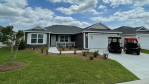 Une maison d’habitation avec un garage, une allée et une pelouse.
