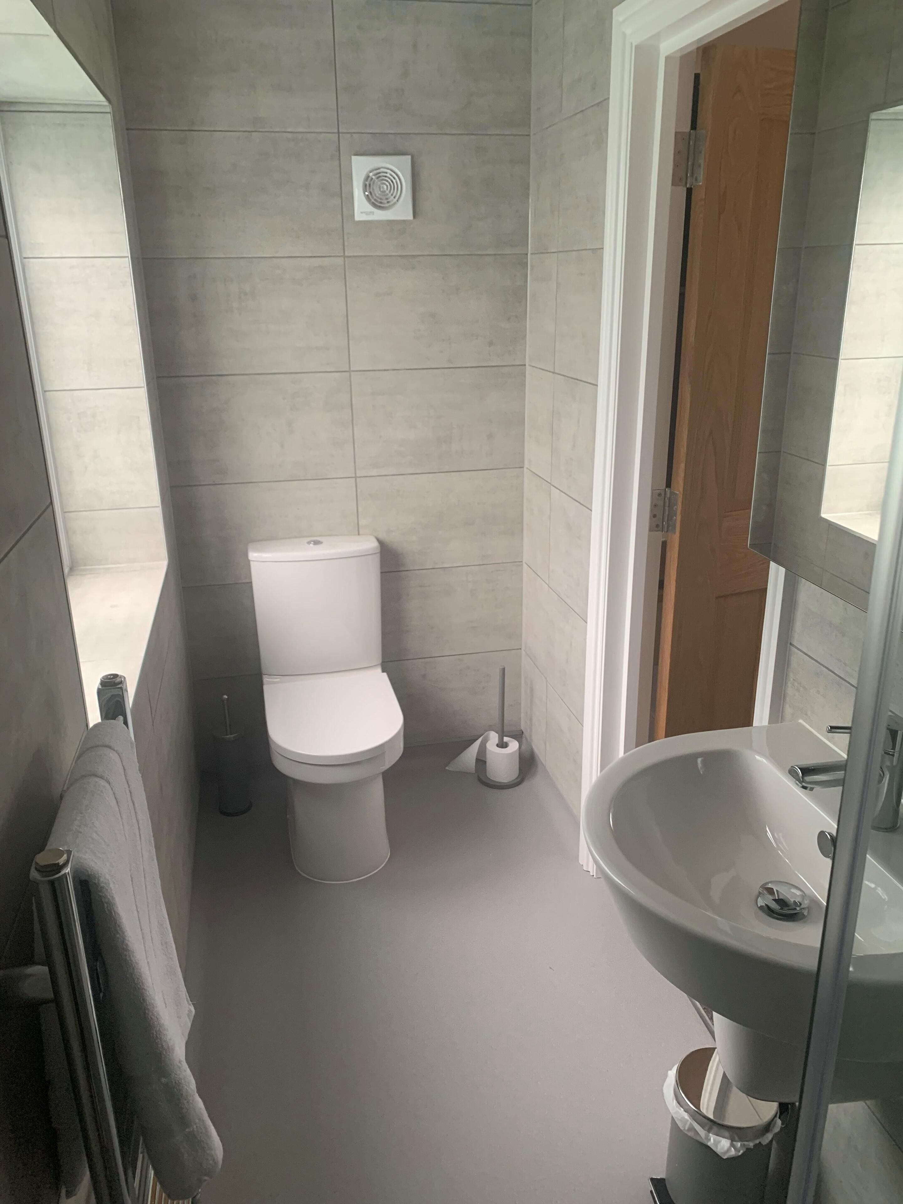 A bathroom with a toilet, a sink, and a shower area.