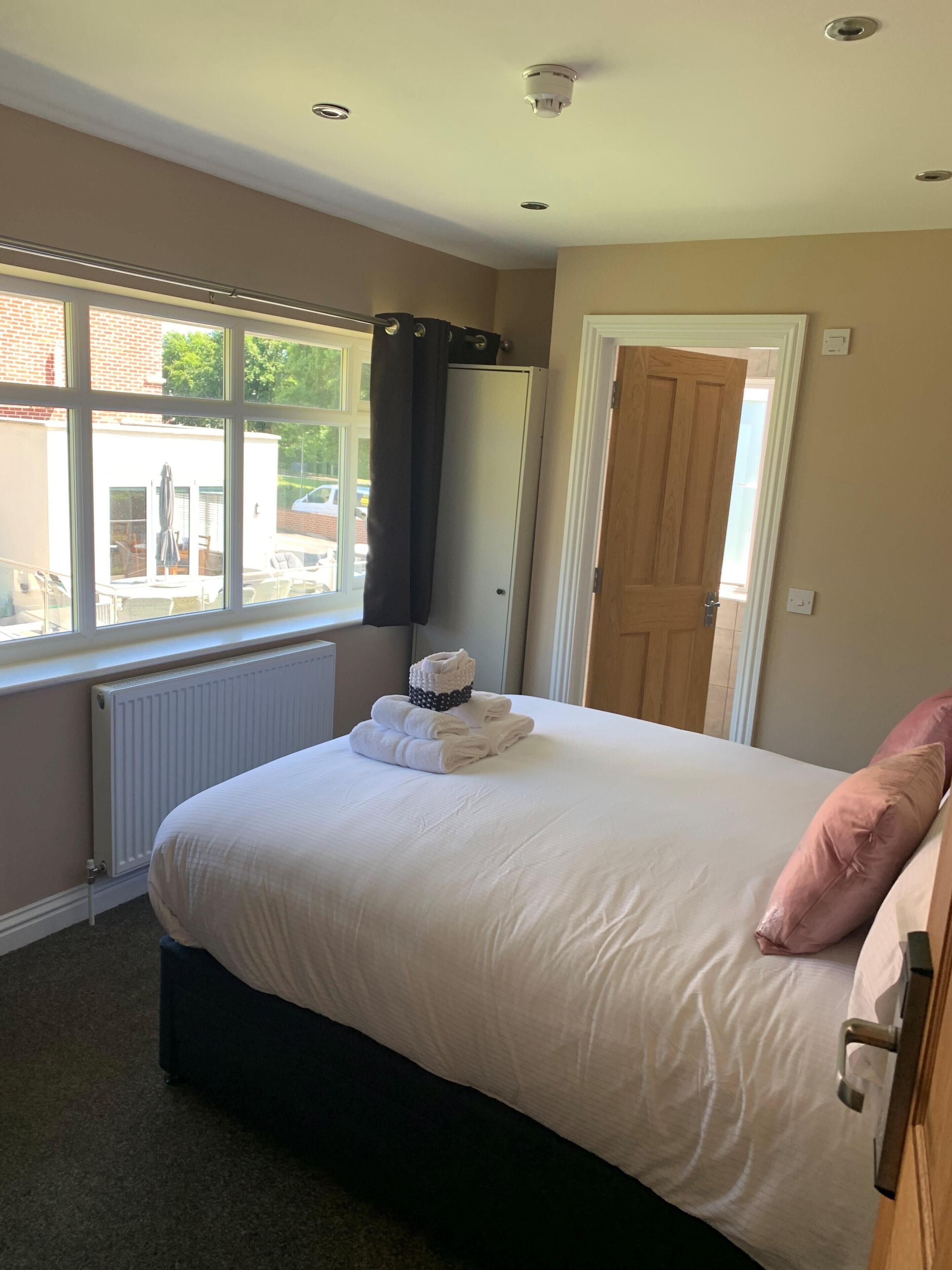 A bedroom with a bed, a radiator, a window, and a door.
