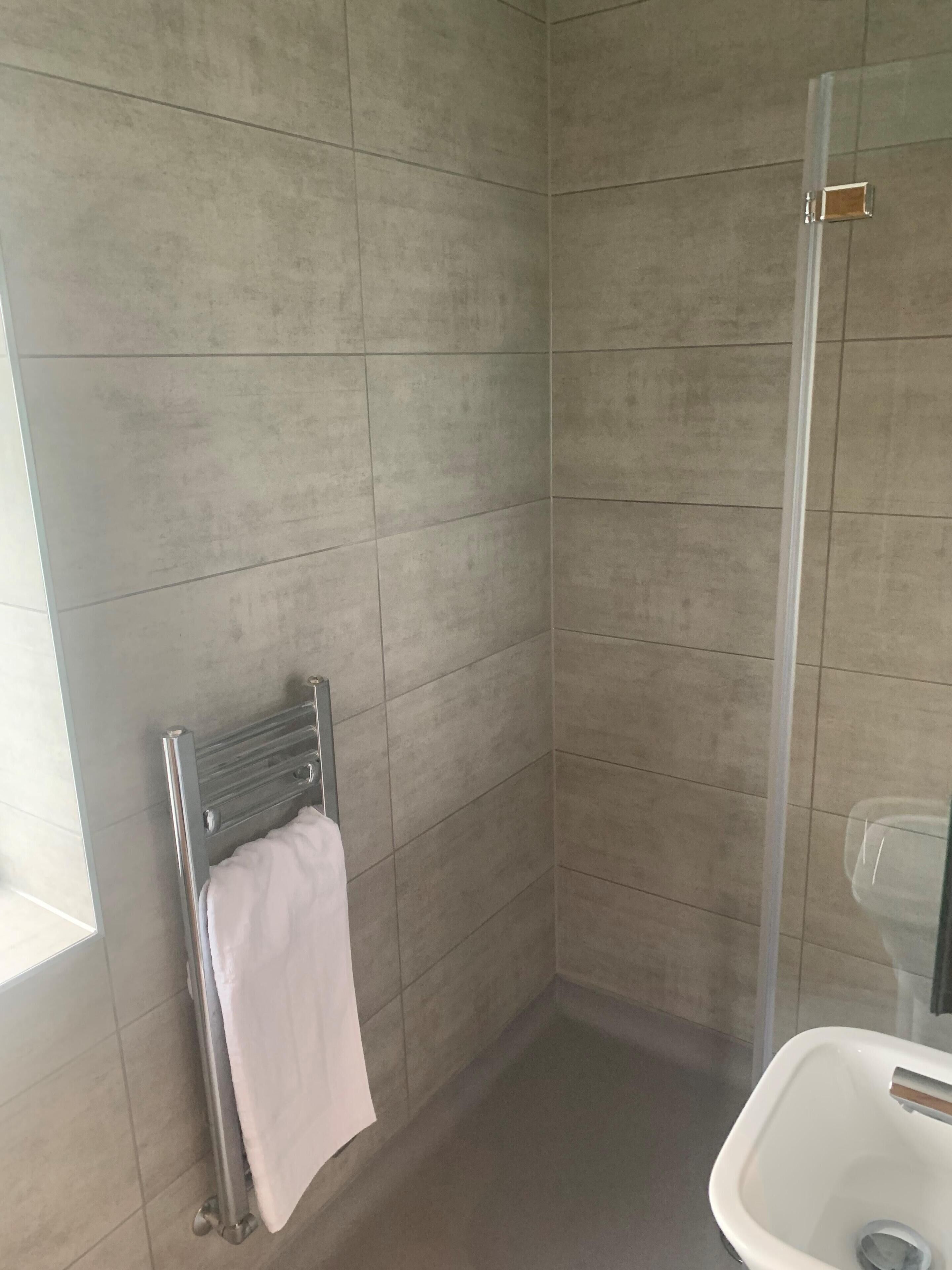 A bathroom with a shower, a toilet, and a towel rack.