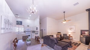En moderne stue med en mørkegrå sofa, et træspisebord og en lysekrone.