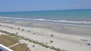 Een strand met een zandstrand, enkele parasols en mensen.