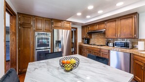 Una cocina moderna con armarios de madera, electrodomésticos de acero inoxidable y encimera de mármol.