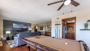 Una mesa de billar en una sala de estar con un sofá y una televisión.