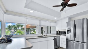 A modern kitchen with a large island, stainless steel appliances, and a view of palm trees outside. - 6341 Managed By Brampton Park (Fort Lauderdale)
