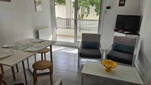 A modern living space with a dining area, two sofas, a TV, and a balcony with a view. - 2-bedroom apartment with terrace and parking, beach 70 metres away (Mauguio)