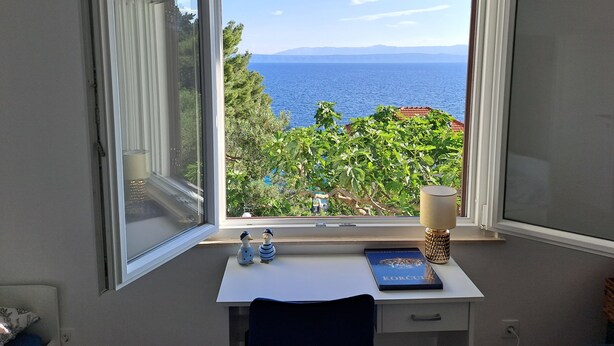 A room with a desk, a window with an open view of the sea and mountains, a lamp, and two decorative ducks. - Korcula vacation home (Blato)