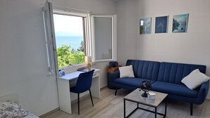 A compact room with a desk, a blue sofa, a small coffee table, and a bed. - Korcula vacation home (Blato)