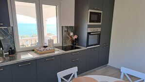 A modern kitchen with dark grey cabinets, a built-in oven, and a microwave. There is a window with a view of the sea. - Korcula vacation home (Blato)