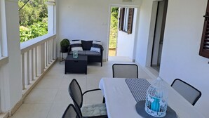 A covered patio area with a dining table, chairs, a sofa, and a small potted plant. - Korcula vacation home (Blato)