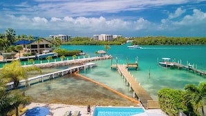 A resort with a clear turquoise sea, a wooden dock, and a swimming pool.