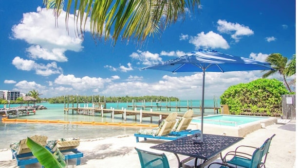 A poolside area with lounge chairs, a table, and an umbrella.