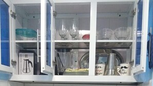 A kitchen with white cabinets, a gas stove, a sink, and various utensils.