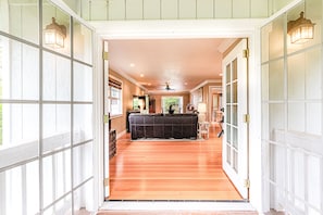 Enter a serene living area with a sofa set and floor-to-ceiling windows offering a view of the outdoors.