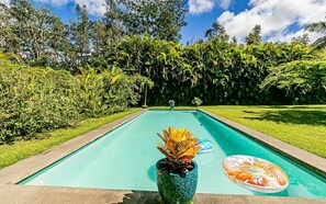 Relax by the serene pool surrounded by lush greenery and trees.