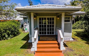 Traditional home with a porch and lush green surroundings.
