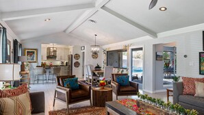 A spacious living room with a high ceiling, a dining area, and a kitchen.