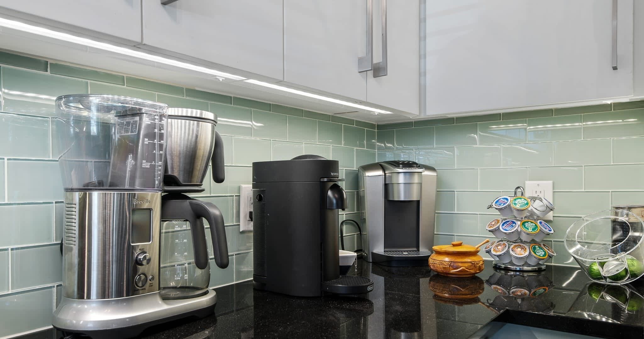 A kitchen with a coffee maker, a blender, and a coffee machine.
