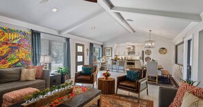 Uma sala de estar moderna com sofá, poltronas, mesa de centro e área de jantar com cadeiras e mesa.