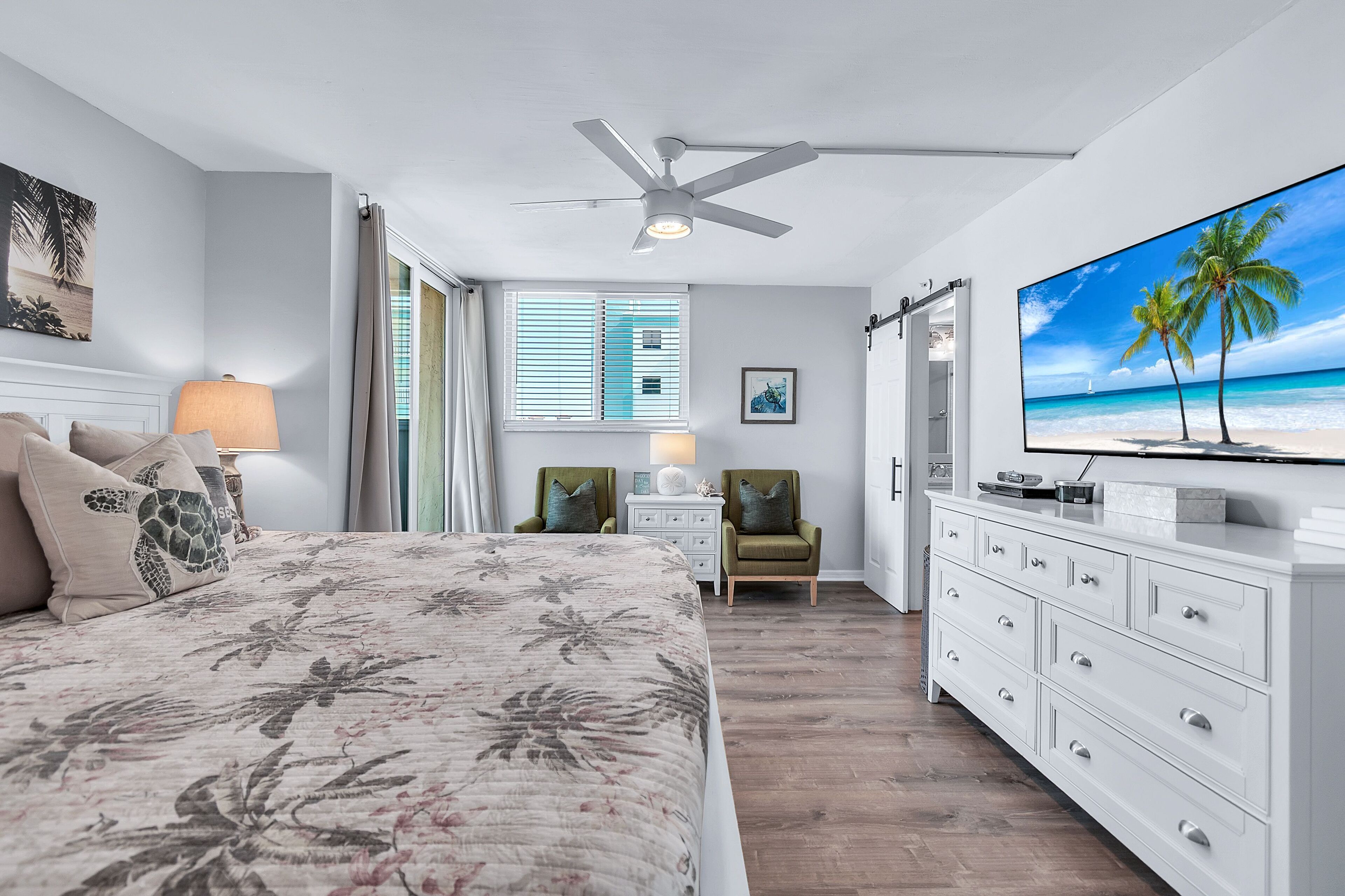 A bedroom with a bed, a TV, a ceiling fan, a nightstand, a chair, and a dresser.