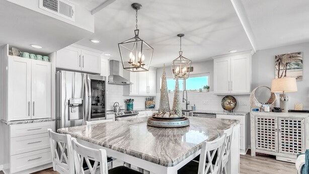 A modern kitchen with white cabinetry, a large marble island, and pendant lighting. - ☀Beachfront Condo🌴Stunning Updates👙Heated Pool🐬Trillium 3A🏖️Beach Access (Madeira Beach)