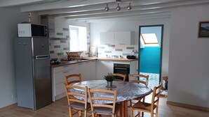 Une cuisine moderne avec un coin repas, des chaises en bois et une vue sur la mer grâce à une fenêtre de toit.