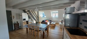 Een moderne keuken met een ingebouwde kookplaat, een koelkast en een eethoek met een tafel en stoelen.