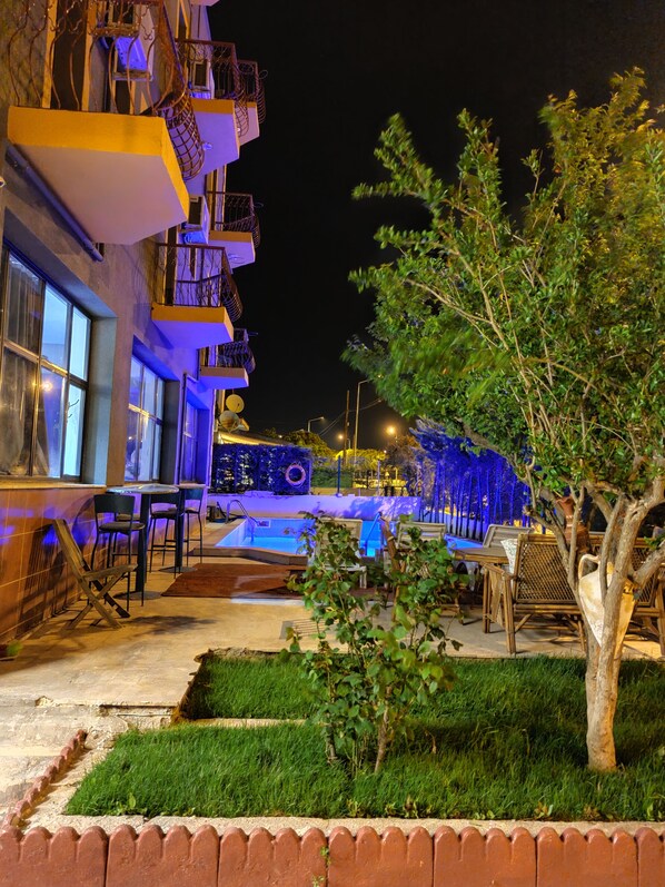A nighttime view of a hotel with outdoor seating, a pool, and a well-lit balcony area. - La Bonita Pansiyon Çeşme Adult Only (+16 yaş) (Cesme)