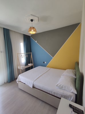 Una camera d'albergo moderna con un letto, una scala in legno e una lampada a sospensione.