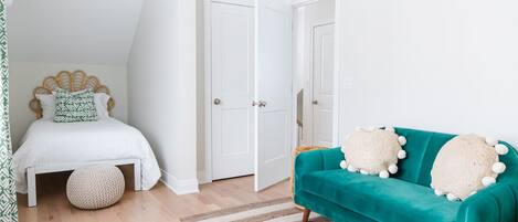 Un dormitorio con una cama, un sofá color turquesa y una alfombra a rayas.
