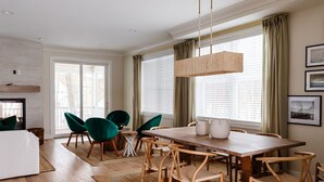 Un espace repas moderne avec une table en bois, des chaises vertes et un luminaire suspendu.