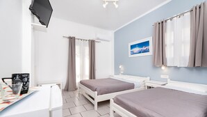 Ett hotellrum med två sängar, ett skrivbord, en platt-TV och ett fönster med gardiner.