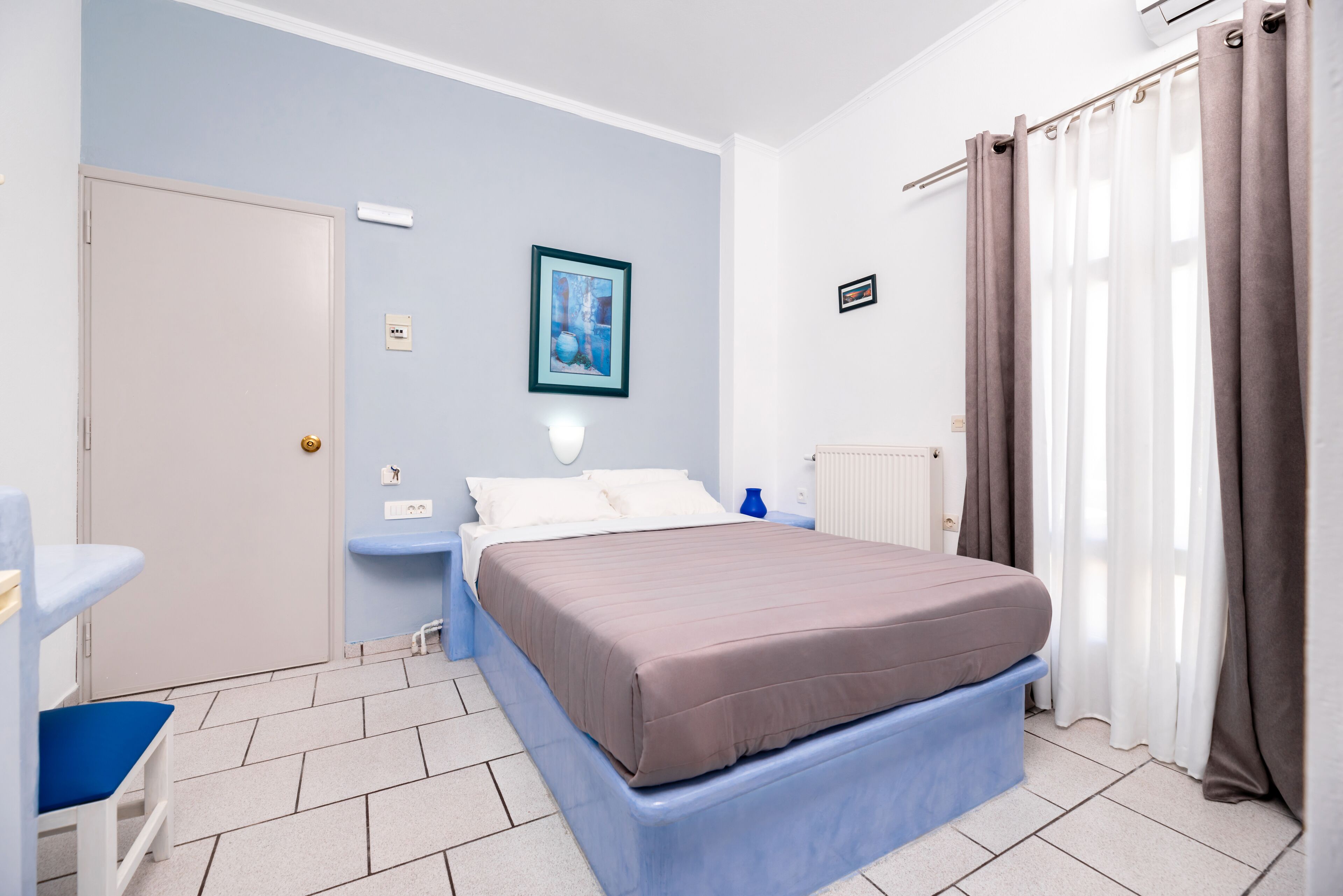 Ein Schlafzimmer mit Bett, Nachttisch, Sessel und einem gerahmten Bild an der Wand.
