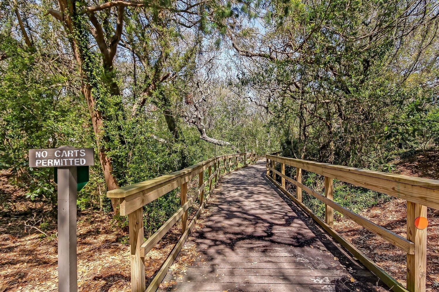 A wooden boardwalk with a 'NO CARTS PERMITTED' sign, surrounded by dense greenery.