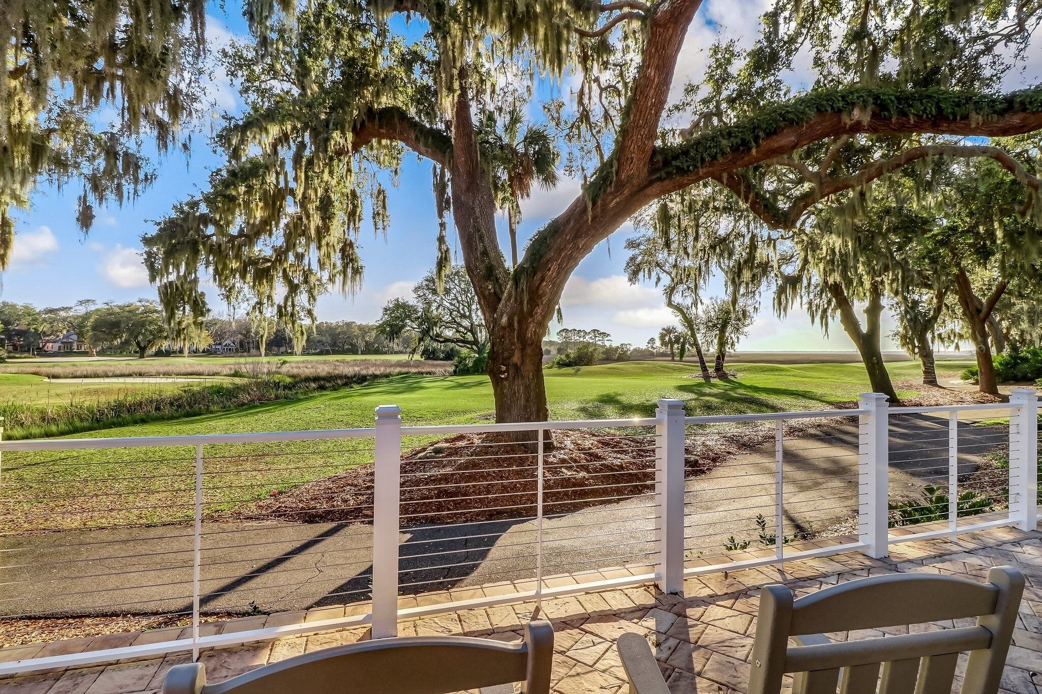 Un patio con vista su un campo da golf e un grande albero con muschio spagnolo.