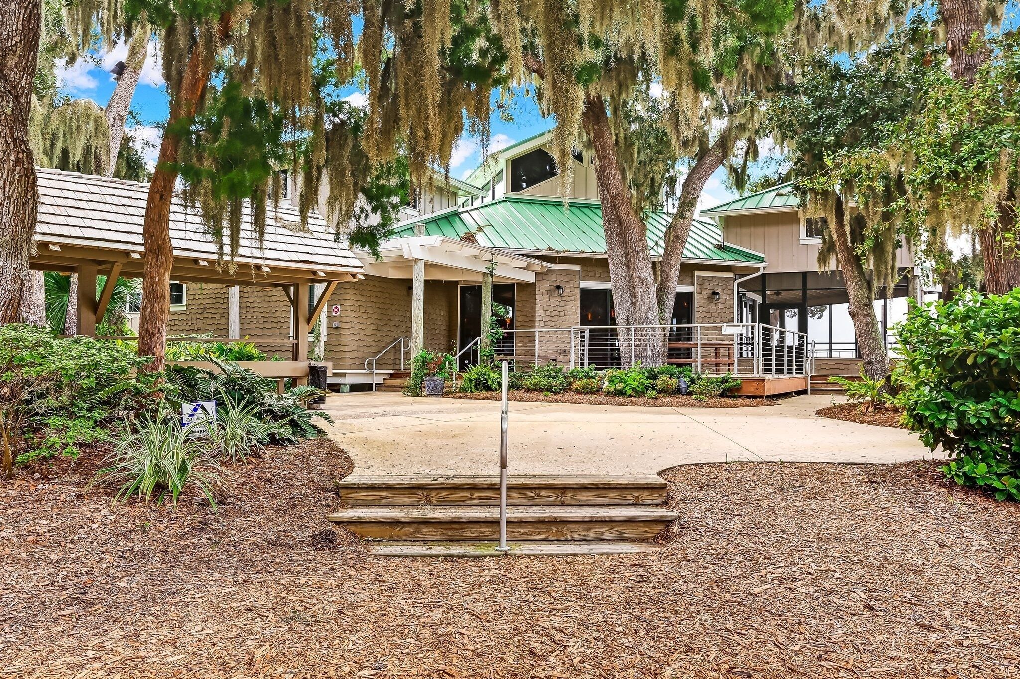 A building with a green roof, wooden steps leading to a covered entrance, and a sign indicating a pet-friendly policy.