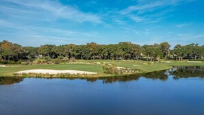 A golf course with a pond in the foreground, surrounded by trees and buildings. - Dog Friendly Beach Wood Condo, Minutes Away from Atlantic Ocean by RedAwning (Fernandina Beach)