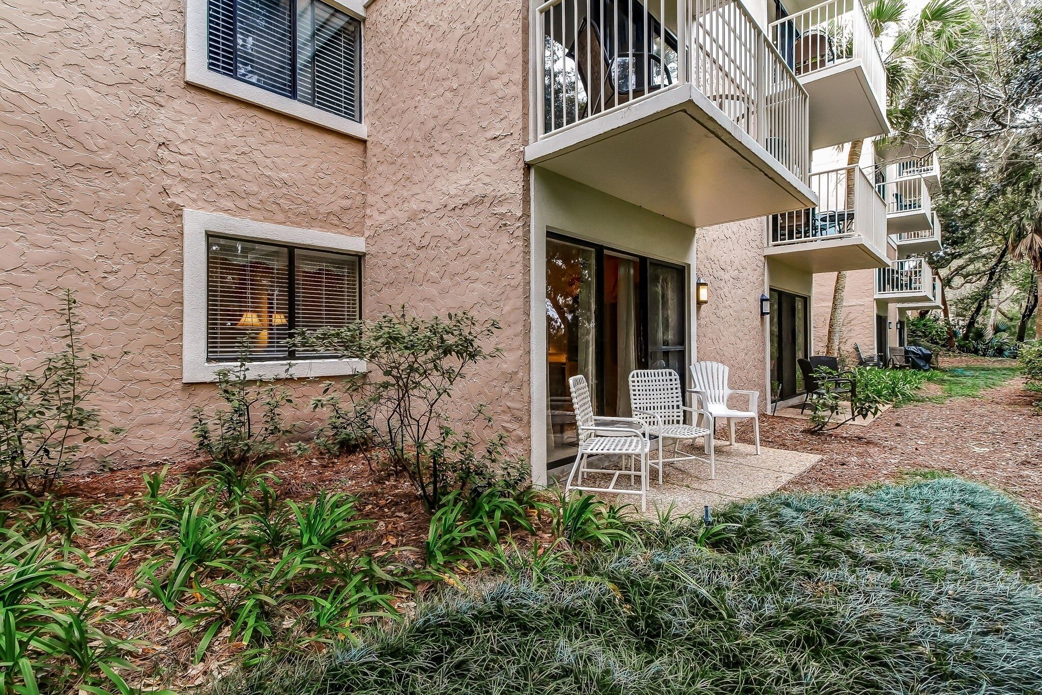 A building with a textured facade, multiple balconies, and a patio area with outdoor furniture.
