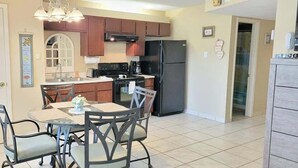 A kitchen with wooden cabinets, a black refrigerator, and a dining table with four chairs.